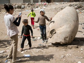 A child poses for a picture past a recently discovered statue in a Cairo slum that may be of pharaoh Ramses II, in Cairo, Egypt, Friday, March 10, 2017. (AP Photo/Amr Nabil)