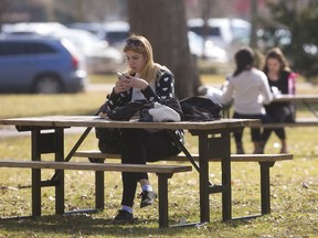 Sonja Ruzic of London Life has a commonly stated opinion of the mild weather that gripped London last month. Ruzic said, "I love it, it's not normal, but it feels good," as she checks her phone during lunch in Victoria Park on Thursday February 23, 2017. (MIKE HENSEN, The London Free Press)