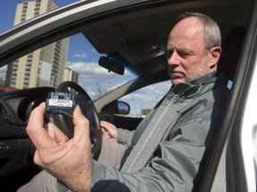 Free Press reporter Randy Richmond shows a recording device that monitors how you drive for a new city hall program called MyCarma London. (MIKE HENSEN, The London Free Press)