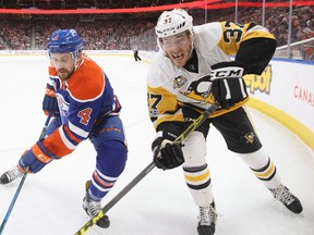 Pittsburgh Penguins' Carter Rowney (37) and Edmonton Oilers' Kris Russell (4) vie for the puck during first period NHL action in Edmonton, Alta., on Friday, March 10, 2017.