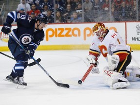 Calgary Flames goalie Brian Elliott (1) knocks the puck away from Winnipeg Jets' Nic Petan (19) during second period NHL action in Winnipeg on Saturday, March 11, 2017. Elliott could be a good fit in a Winnipeg Jets jersey. THE CANADIAN PRESS/John Woods