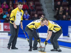 Manitoba skip Mike McEwen (left) follows as Matt Wozniak and Denni Neufeld (right) sweep against Northern Ontario in bronze medal action at the Tim Hortons Brier curling championship at Mile One Centre in St. John's on Sunday, March 12, 2017. (Andrew Vaughan/The Canadian Press