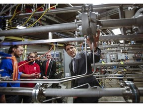 Prime Minister Justin Trudeau, right, listens as Craig Lawson MacKenzie, left, and Jesse Rafael Rodriguez, second from left, explain a flow lab during a tour of the MacPhail School of Energy at the Southern Alberta Institute of Technology Polytechnic in Calgary, Dec. 21, 2016. (THE CANADIAN PRESS/Jeff McIntosh)