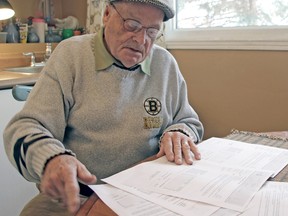 Joe Steele looks through his Hydro One bills at his kitchen table at his home in Powassan. (Gord Young/Postmedia Network)