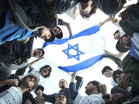 Jewish students gather around an Israeli flag during an anti-hate rally in North York several years ago. New Toronto Police Services Board report shows hate crimes target Jews more than any other community in the city. (TORONTO SUN/FILES)
