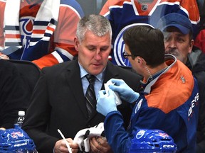 An Edmonton Oilers trainer tends to assistant coach Jim Johnson after getting hit by the puck against the Montreal Canadiens at Rogers Place on Sunday, March 12, 2017. (Ed Kaiser)