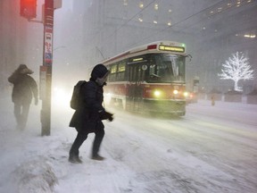 A person makes their way to a streetcar as snow flies through the air during a squall in downtown Toronto, on Thursday, December 15, 2016. (THE CANADIAN PRESS/Graeme Roy)