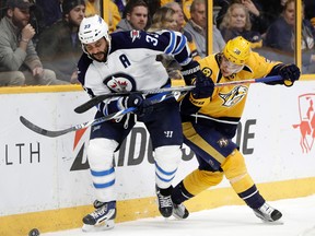 Jets defenceman Dustin Byfuglien (left) and Predators winger Viktor Arvidsson battle for the puck during the second period in Nashville on Monday night. (The Associated Press)