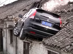 A SUV landed on the roof of a home after skidding off a road in Taizhou City, Jiangsu Province of China. (Screengrab)