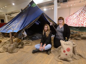 Monica Grunwald, left, and Dana Mero, both second-year fine arts students at Fanshawe College, sit outside First World War tents forming part of an arts installation at The Arts Project celebrating the 100th anniversary of Vimy Ridge. (MORRIS LAMONT, The London Free Press)