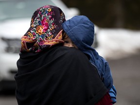 A mother and child from Turkey wait to be put into a police vehicle by the RCMP after they crossed into Canada from the United States at Hemmingford, Que., last month. (GETTY IMAGES)