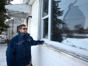 London bylaw officer Wade Jeffery looks over a smashed window at a home on Clarke Road that was recently used as a group home for vulnerable adults. (MORRIS LAMONT, The London Free Press)