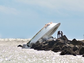 In this Sept. 25, 2016, file photo, investigators inspect an overturned boat as it rests on a jetty after a crash off Miami Beach, Fla. (AP Photo/Gaston De Cardenas, File)