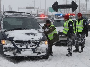 SQ and MUC officers try to clear up Highway 520 near Cavendish road on Wednesday March 15, 2017 following massive snow storm that left many motorists stranded overnight. (Pierre Obendrauf / MONTREAL GAZETTE)