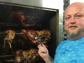 Robbie Johnston of Speedy's BBQ shows off pork shoulders on his gas rotisserie.