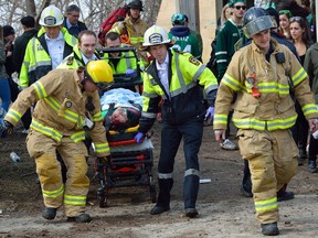 Emergency workers remove an injured student who fell down a steep drop-off that leads to Harris Park in the backyard of a house on Ridout Street where a St Patrick's day party was underway on Friday. (MORRIS LAMONT, The London Free Press)