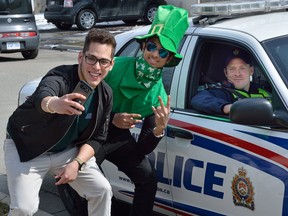 Mauro Godoy, left, and Lakshan Geegana take a selfie with a police officer parked in a car on Broughdale Ave during St. Patrick's day celebrations on Friday March 17, 2017. (London Free Press file photo)