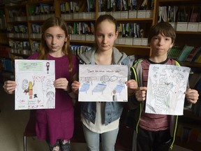 Grade 6 students Kaleigh Doud, Anika Hoff, and Eric Buck from Pilot Butte School in Pilot Butte, Sask., in  hold illustrations inspired by Gord Downie’s album and graphic novel, Secret Path. The story is about 12-year-old Chanie Wenjack, who died while trying to walk home after running away from residential school in 1966. (MICHAEL BELL/Regina Leader-Post)