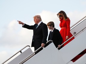 U.S. President Donald Trump with his wife first lady Melania Trump and their son Barron Trump, points to the applauding crown as they disembark from Air Force One upon arrival at Palm Beach International Airport in West Palm Beach, Fla., , Friday, March 17, 2017. (AP Photo/Manuel Balce Ceneta)