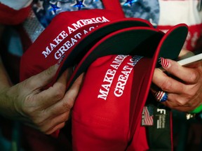 In this June 2, 2016, file photo, a woman holds hats to get them autographed by Republican presidential candidate Donald Trump during a rally in San Jose, Calif. The New York Post reported on March 19, 2017, that a Philadelphia man sued a New York City bar, claiming he was denied service for wearing such a hat. (AP Photo/Jae C. Hong, File)