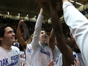 The Oak Park Raiders celebrate with the trophy after beating the St. Paul’s Crusaders to win the AAAA provincial basketball title at the University of Manitoba on Monday night. (Kevin King/Winnipeg Sun)