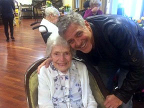 In this photo taken on Sunday, March 19, 2017, US actor George Clooney visits 87-year-old Pat Adams at Sunrise of Sonning Retirement and Assisted Living Facility in Reading, England. Actor George Clooney startled an 87-year-old fan in Britain by showing up at her assisted living facility with flowers and a card to wish her a happy birthday. (Linda Jones/Sunrise of Sonning Retirement and Assisted Living Facility via AP)