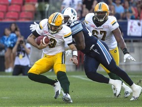 Eskimos quarterback Mike Reilly (left) slips away from Argonauts' Shawn Lemon during CFL action in Toronto on Aug. 20, 2016. (Chris Young/The Canadian Press)