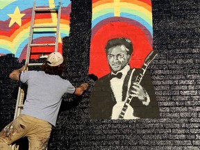 Joe Albanese replaces an old mural with a new painting that will feature the album cover of a new Chuck Berry album at Delmar Loop in St. Louis on Saturday, March 18, 2017. They were surprised to hear that the music legend died as they were working on the project. Earlier in the day, police announced Berry died at the age of 90. (David Carson/St. Louis Post-Dispatch via AP)