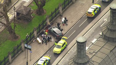 In this image taken from video  police officers gather around a car adjacent to  Houses of Parliament in London, Wednesday, March 23, 2017 after the House of Commons sitting was suspended as witnesses reported sounds like gunfire outside. The leader of Britain's House of Commons says a man has been shot by police at Parliament. David Liddington also said there were "reports of further violent incidents in the vicinity." (ITN via AP) ORG XMIT: LON833