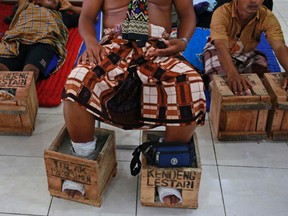 In this March 19, 2017 photo, villagers from Kendeng, Central Java who has their feet encased in concrete in protest against the operation of a cement factory near their villages, rest at their temporary shelter at the Legal Aid Institute office in Jakarta, Indonesia. Dozens of farmers and activists opposed to the factory have encased their feet in concrete during a days-long protest in Jakarta, the capital. Farmers in the village of Kendeng have battled against plans for the factory for years, saying it could taint their water. (AP Photo/Dita Alangkara)