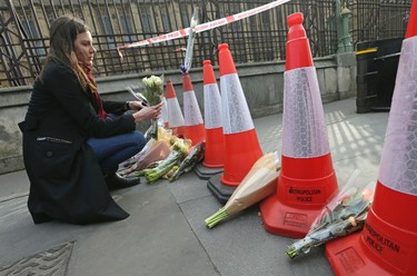 A woman looks at floral tributes to the victims of Wednesday's attack placed near the Houses of Parliament in London, Thursday March 23, 2017. On Wednesday a knife-wielding man went on a deadly rampage, first driving a car into pedestrians then stabbing a police officer to death before being fatally shot by police within Parliament's grounds in London. (AP Photo/Tim Ireland)