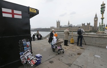 People walk past a souvenir stall on Westminster Bridge after it was re-opened to the public Thursday, March 23, 2017, following an attack on Wednesday when a man drove a car into pedestrians then stabbed a police officer to death before being fatally shot by police within Parliament's grounds. The IS-linked Aamaq news agency said Thursday that the person who carried out the "attack in front of the British parliament in London was a soldier of the Islamic State." (AP Photo/Tim Ireland)
