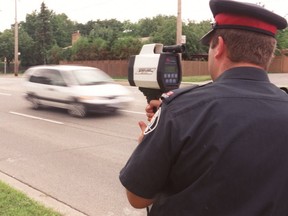 A police officer uses a radar gun to catch speeders. (SUN FILES)