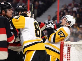 Senators' Zack Smith (15) grabs on to Penguins' Sidney Crosby (87) during first period NHL action in Ottawa on Thursday, March 23, 2017. (Justin Tang/The Canadian Press)