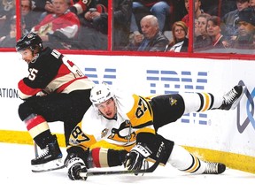 Erik Karlsson gets tangled up with the Pens' Sidney Crosby on Thursday. (The Canadian Press)