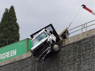 Emergency crews and tow truck workers tend to a truck hanging over an embankment on Highway 17 in Surrey.  (Postmedia Network)