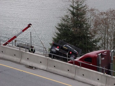 Emergency crews and tow truck workers tend to a truck hanging over an embankment on Highway 17 in Surrey.  (Postmedia Network)