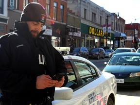 Const. Fil Wisniak, curator of the new @kp_beatcop Twitter and Instagram handle, downtown Kingston, Ont. on Wednesday March 22, 2017. Steph Crosier/Kingston Whig-Standard