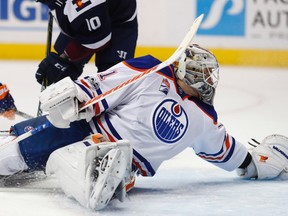 Edmonton Oilers goalie Laurent Brossoit, front, makes a backhanded glove save of a shot by Colorado Avalanche right wing Sven Andrighetto, back right, of Switzerland, as Oilers right wing Jordan Eberle defends during the third period of an NHL hockey game Thursday, March 23, 2017, in Denver. Edmonton won 7-4.