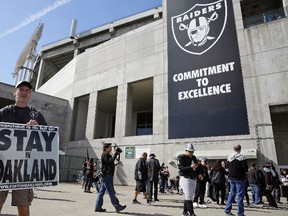 John P. Kelleher holds up a sign outside the Oakland Coliseum before the start of a rally to keep the Oakland Raiders from moving Saturday, March 25, 2017, in Oakland, Calif. (AP Photo/Eric Risberg)