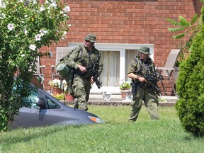 OPP officers carry rifles as they walk along Westgate Avenue, near a home at 212 Park Street where terrorism suspect Aaron Driver was shot and killed by police Wednesday, in Strathroy, Ont. on Thursday August 11, 2016. (Free Press file photo)