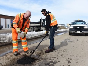 City of Grande Prairie crew member Connan Mountney rakes the city's new cold-mix in a pothole while colleague Tom Knott sprinkles water onto the hole on 112 Street and 96 Avenue on Monday in Grande Prairie, Alta. The new cold-mix is supposed to be more durable and a better filler than a traditional cold-mix. The city has filled about 3,000 potholes. 
Svjetlana Mlinarevic/Daily Herald-Tribune