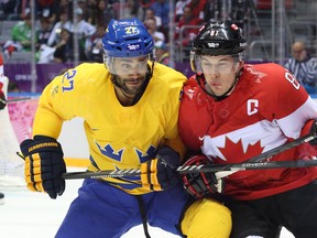 Sidney Crosby of Canada (right) battles against Johnny Oduya of Sweden during first period action of the gold medal game at the 2014 Winter Olympic Games in Sochi, Russia, on Feb. 23, 2014. (Jean Levac/Postmedia Network/Files)