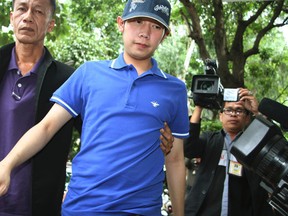 In this Sept. 3, 2012, photo, Vorayuth "Boss" Yoovidhya, centre, whose grandfather co-founded energy drink company Red Bull, is escorted by police in Bangkok, Thailand.  (Thai Daily News via AP)