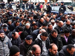 French riot police officers stand next to Muslims praying in the street during a protest in front of the city hall of Clichy, near Paris, on March 24, 2017, after an unauthorised place of worship was closed by local authorities. (AFP/PHOTO)