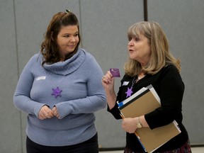 Domestic violence survivor Sarah Wilson, left, with Deb Wood holding a Purple Posse card advising domestic violence victims where to turn for help in the Kingston area as part of the Purple Posse Initiative on Tuesday. (Ian MacAlpine /The Whig-Standard)