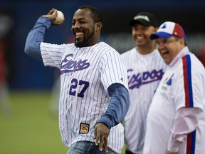 Former Montreal Expos slugger Vladimir Guerrero throws a ceremonisl pitch next to Montreal mayor Denis Coderre (right) and former teammate Orlando Cabrera during a pre-game ceremony as the Blue Jays face the Reds in MLB exhibition play in Montreal on April 3, 2015. (Paul Chiasson/The Canadian Press/Files)