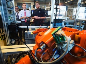 Minister of Finance Bill Morneau, centre, operates a robot with student Spencer Pelzer, right, while Calgary Mayor Naheed Nenshi looks on during their tour of the robotics lab at the Southern Alberta Institute of Technology in Calgary, Alta., on Monday. Should we be preparing for the coming invasion of job-stealing, career-crushing robots? It's a question that's moved from science-fiction novels to the tip of policy-makers' tongues. (THE CANADIAN PRESS/PHOTO)