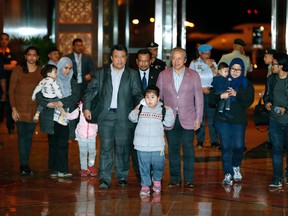 Malaysians who were stranded in Pyongyang walk with Malaysia's Foreign minister Anifah Aman, center right, after arriving at Kuala Lumpur International airport in Sepang, Malaysia, Friday, March 31, 2017. Malaysia said Thursday it has agreed to release the body of Kim Jong Nam to North Korea in exchange for the return of nine Malaysians held in the North's capital. (AP Photo/Vincent Thian)