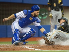 Pirates' Adam Frazier (right) is tagged out at home by Blue Jays catcher Russell Martin during fifth inning preseason MLB action in Montreal on Friday, March 31, 2017. (Paul Chiasson/The Canadian Press)